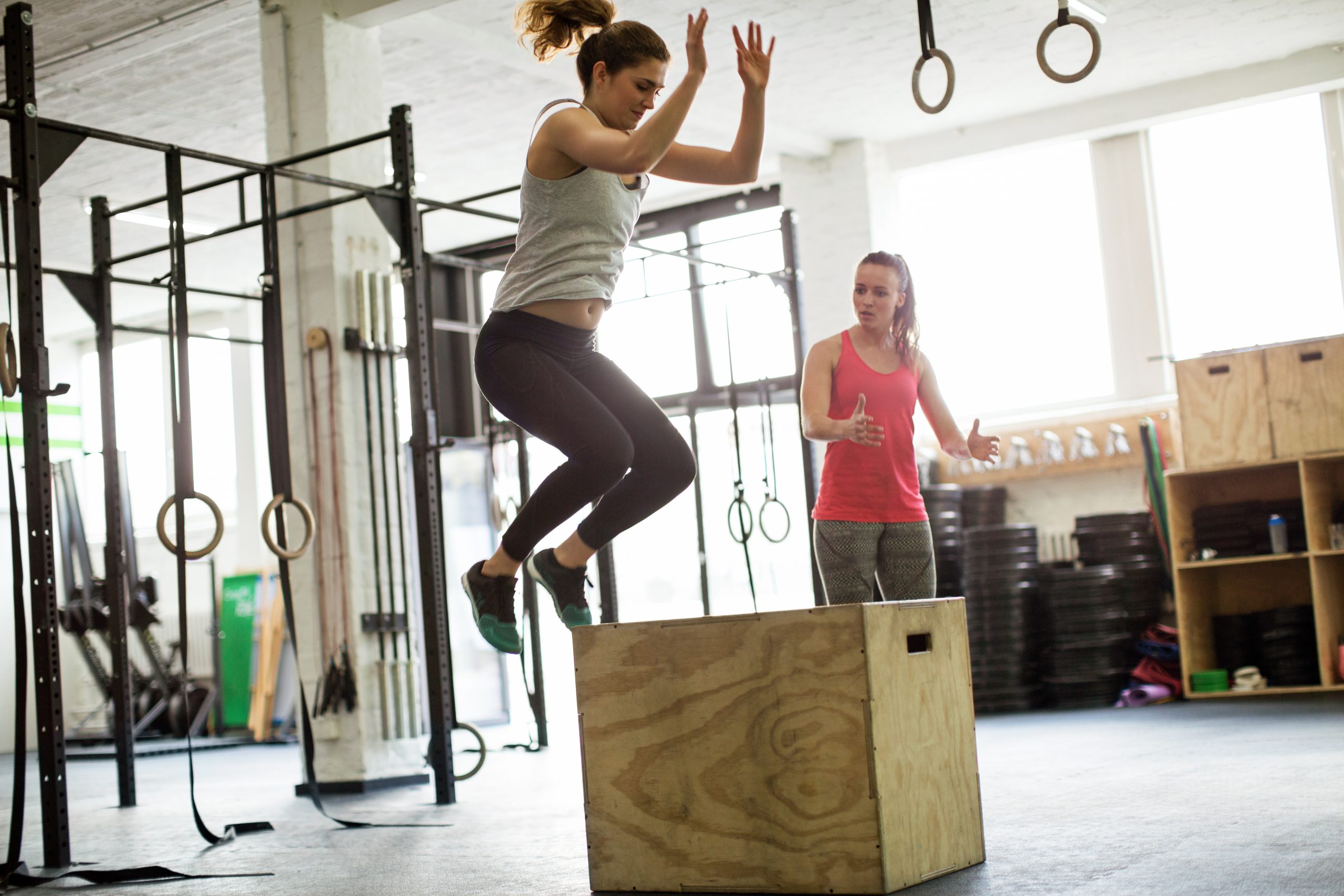 Woman jumping on box with fitness trainer Jonge vrouw in sportkleding die een yoga positie aanneemt
