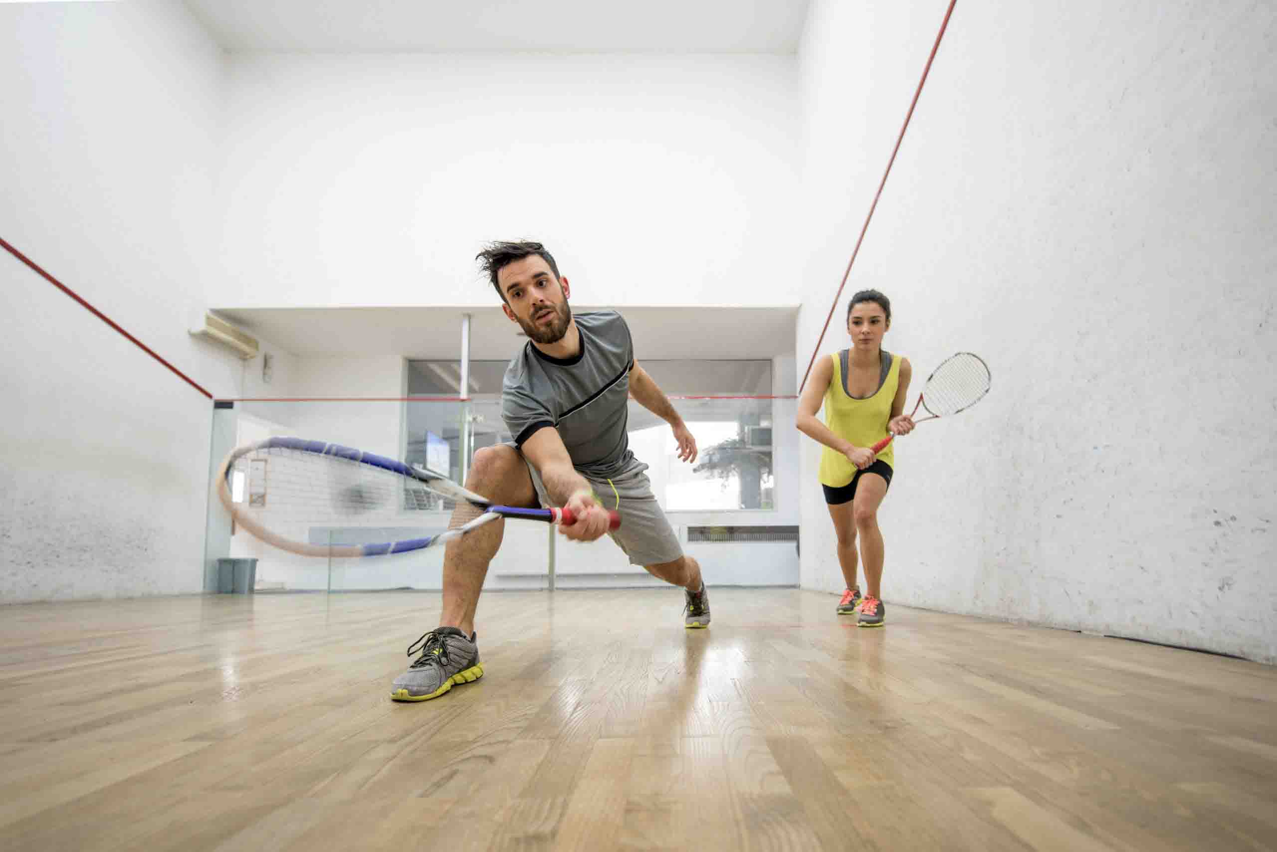 Een jonge man met een squash racket die squash speelt